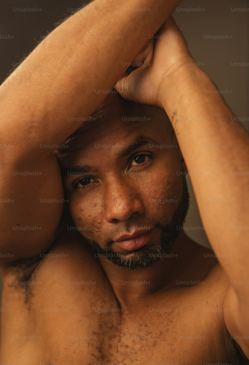 a close up of a shirtless man with his hands on his head