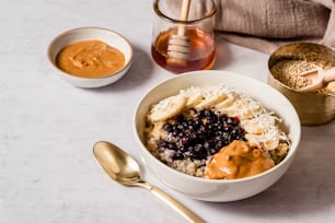 a bowl of oatmeal with bananas, blueberries, and peanut butter