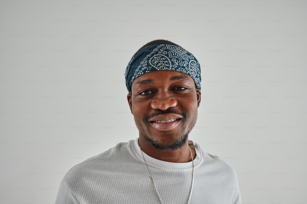 a man wearing a bandana smiles at the camera