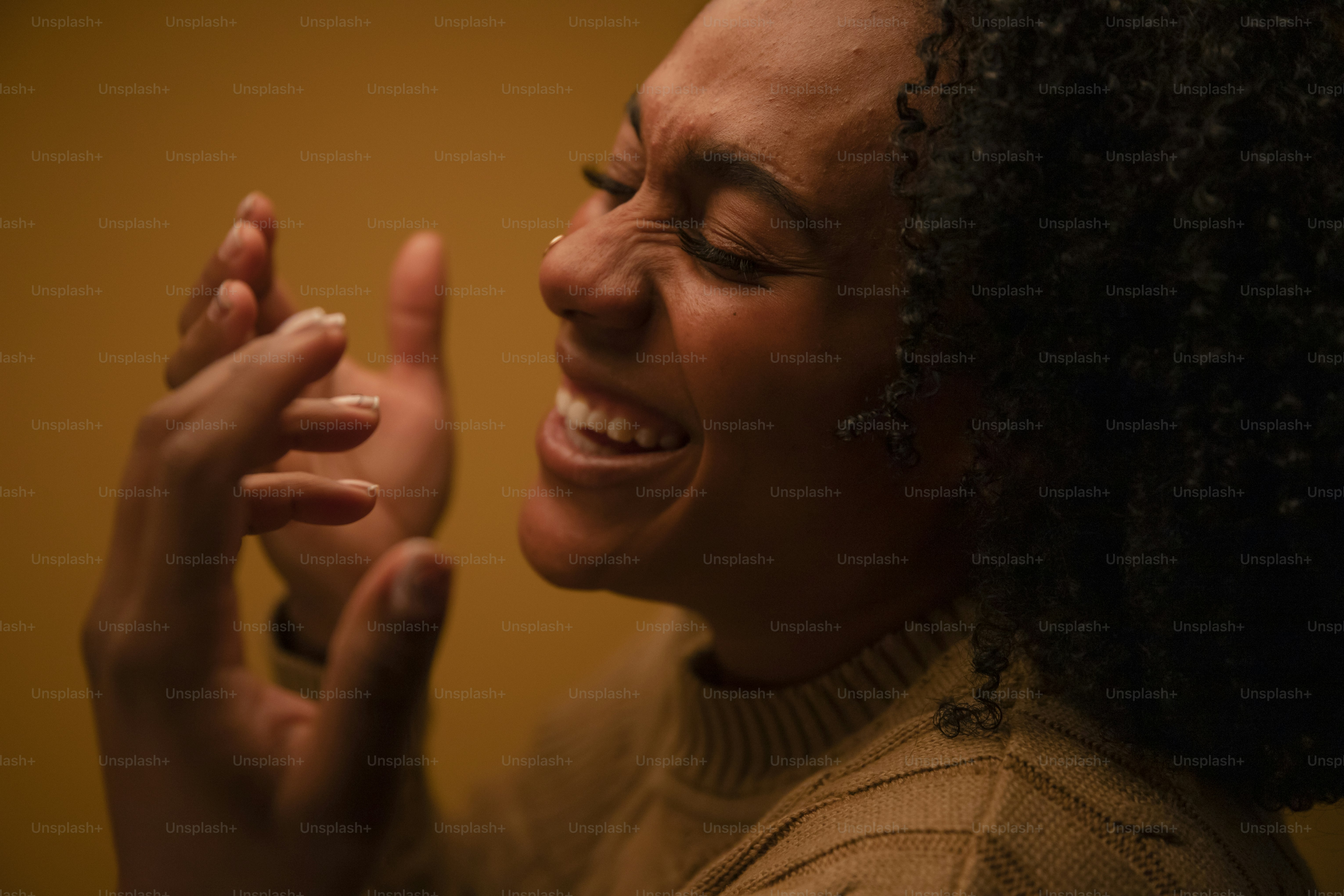 A woman with curly hair laughs heartily laughs.