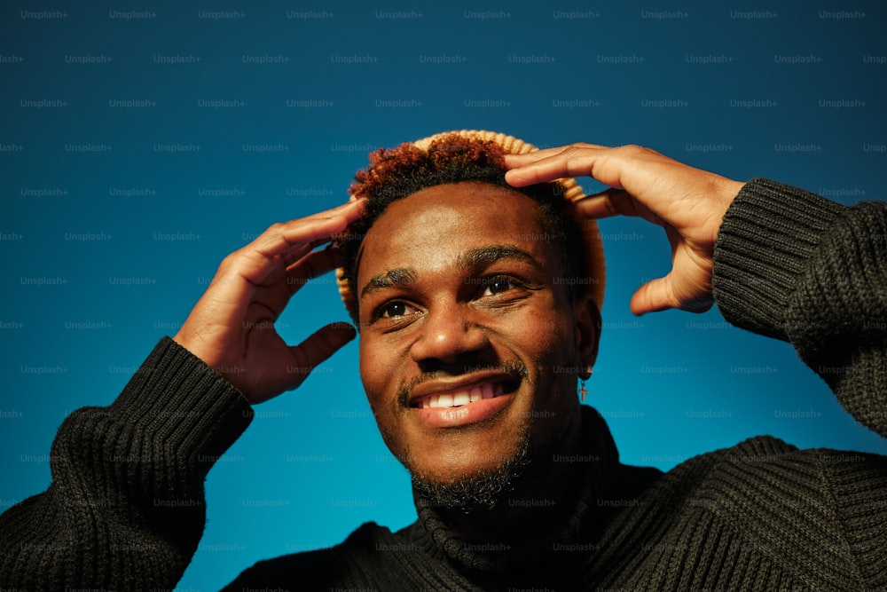 a man is smiling and holding his hair up