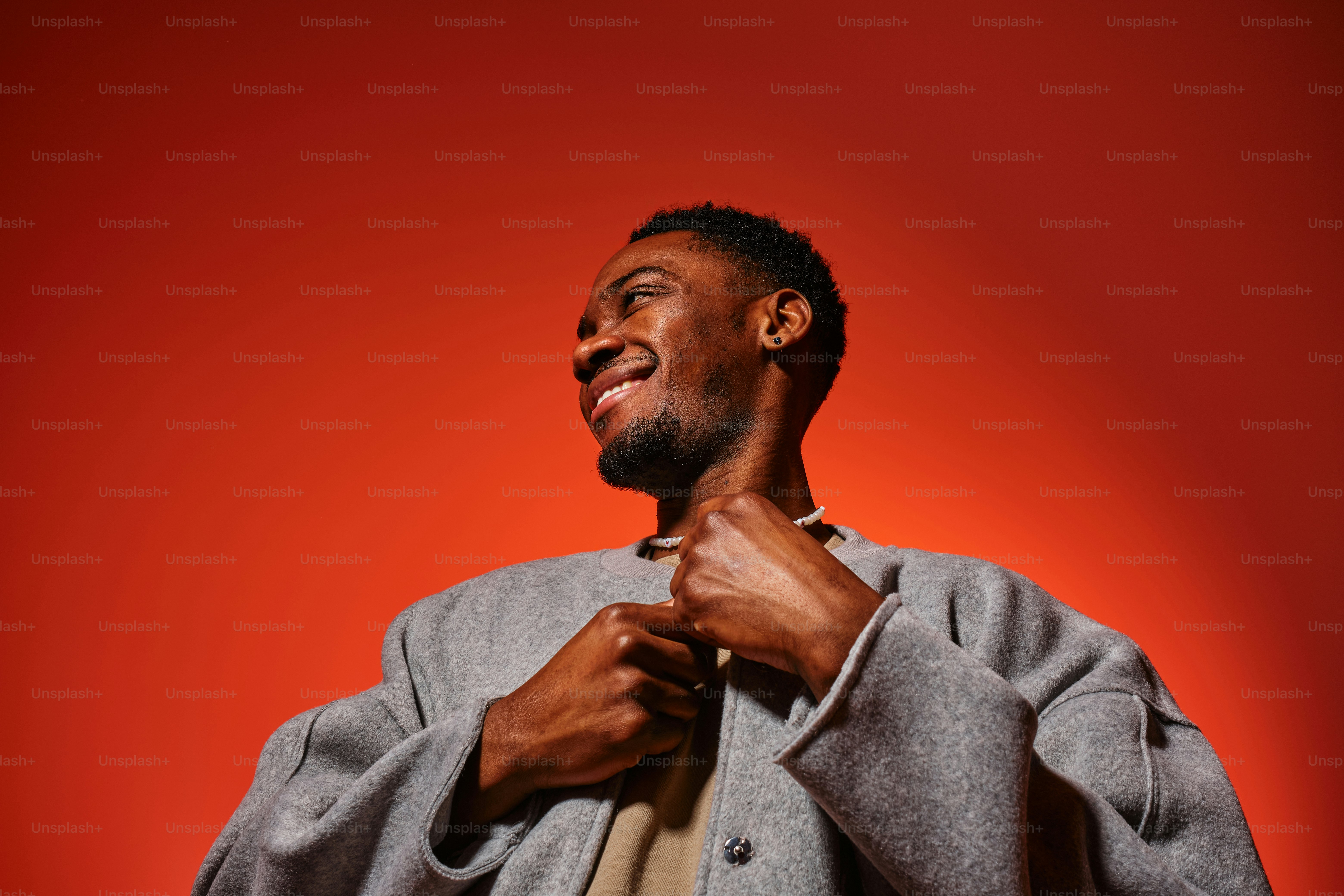 Un hombre con una chaqueta gris y un fondo rojo