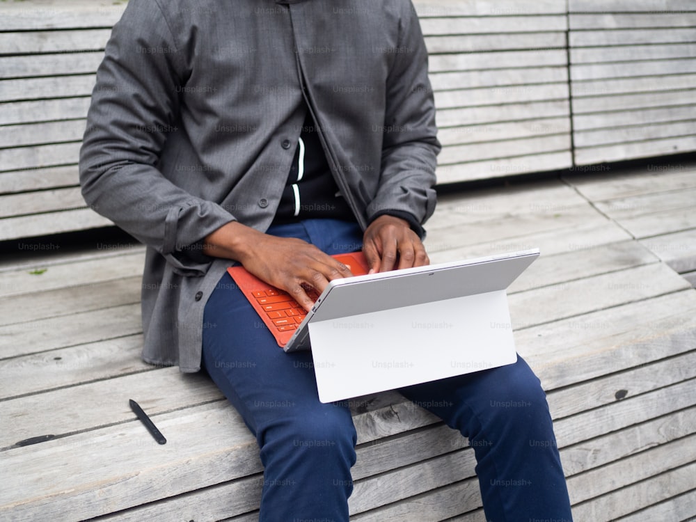 um homem sentado em um banco usando um computador portátil