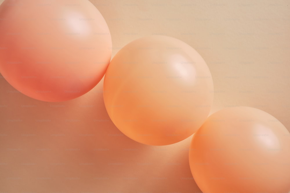 Três balões coloridos de pêssego em um fundo bege