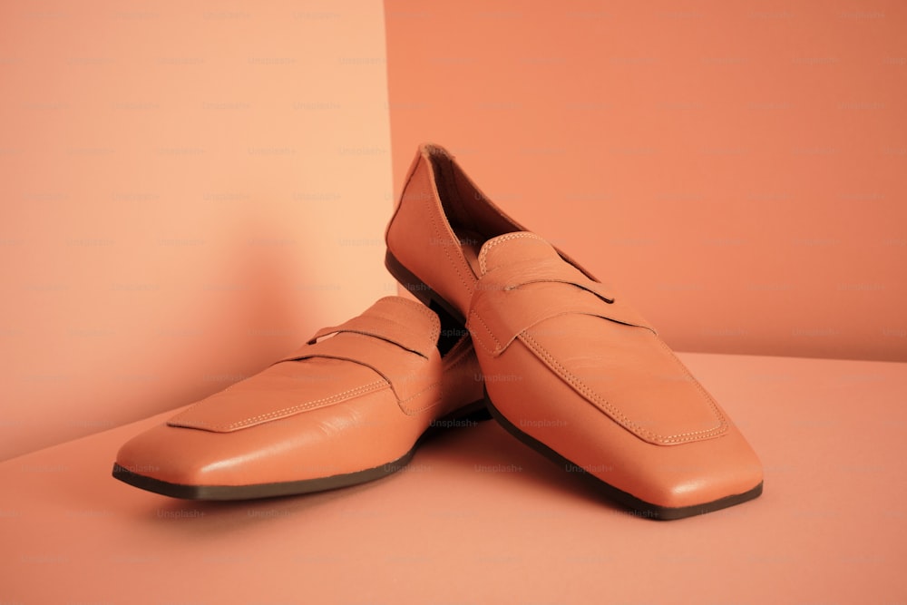 a pair of tan shoes sitting on top of a pink floor