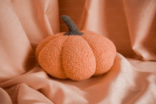 una piccola zucca arancione seduta sopra un letto