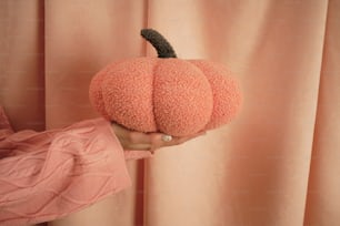 a person holding a fake pumpkin in their hand