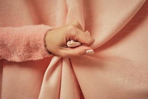 La mano de una mujer sobre una tela rosa