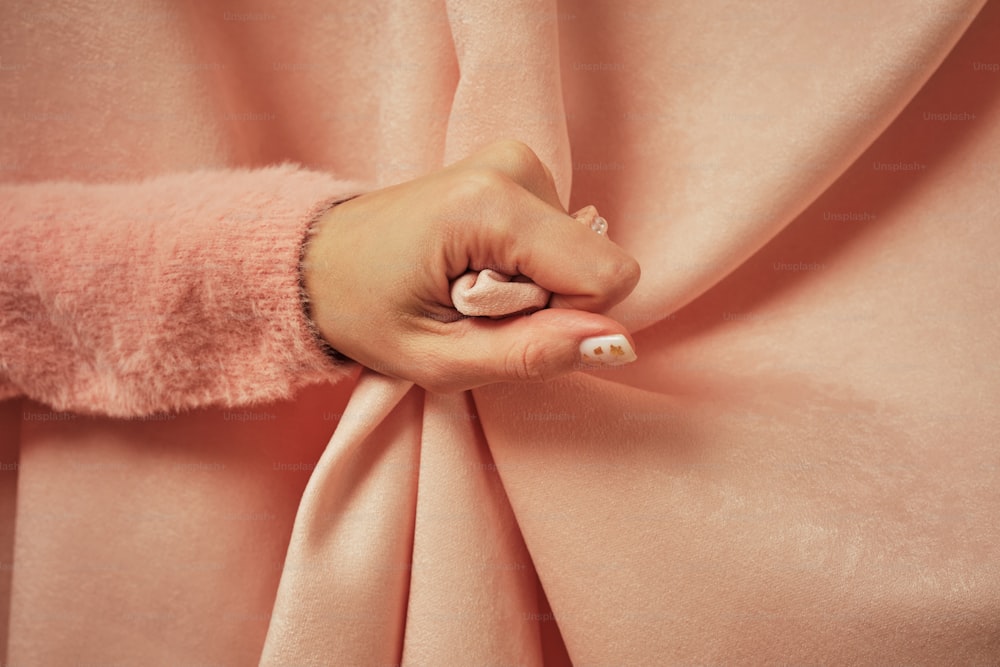 a woman's hand on a pink fabric