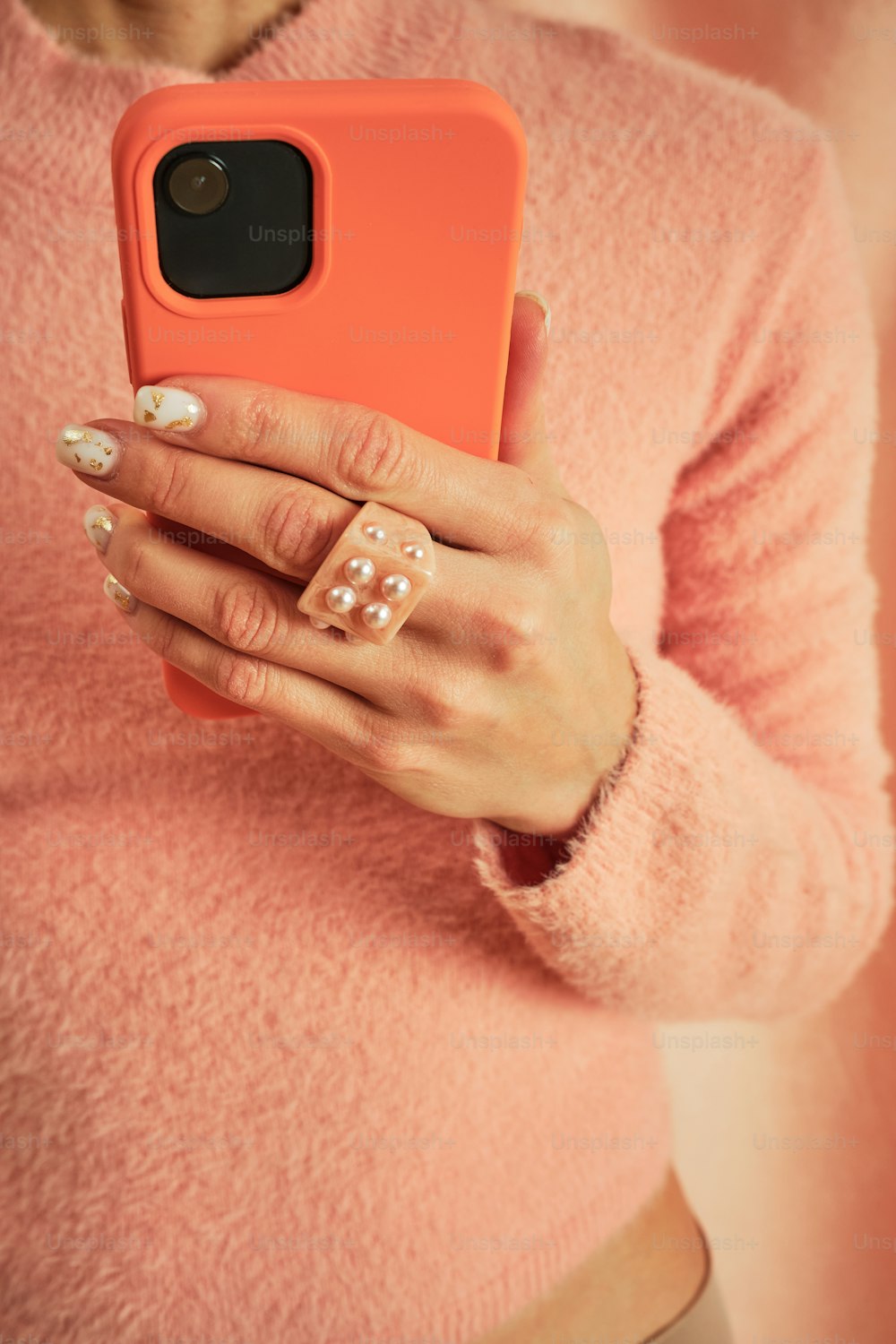 a woman in a pink sweater holding a cell phone