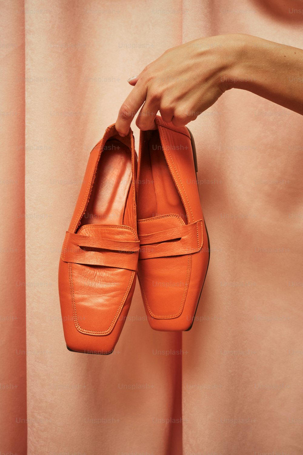 une personne tenant une paire de chaussures orange ;