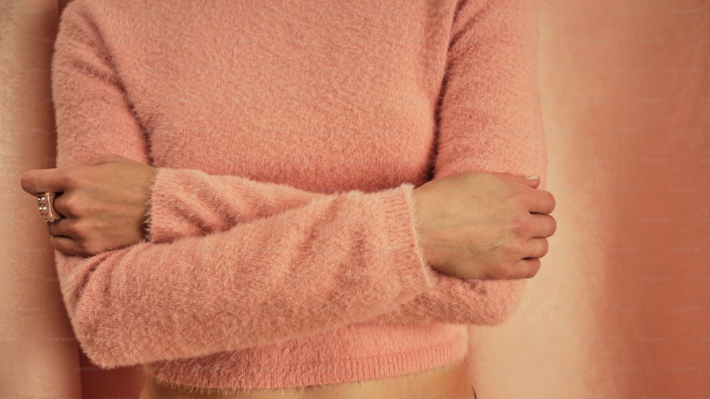 �ピンクのセーターを着た女性が腰に手を当てている
