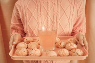 a woman holding a tray of cookies and a glass of water