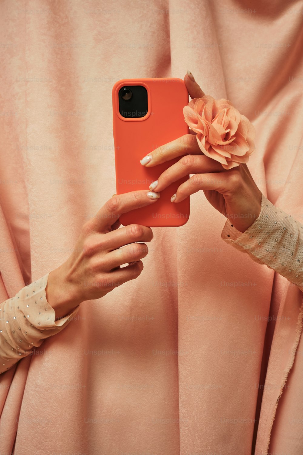 a woman holding a cell phone with a flower in her hand