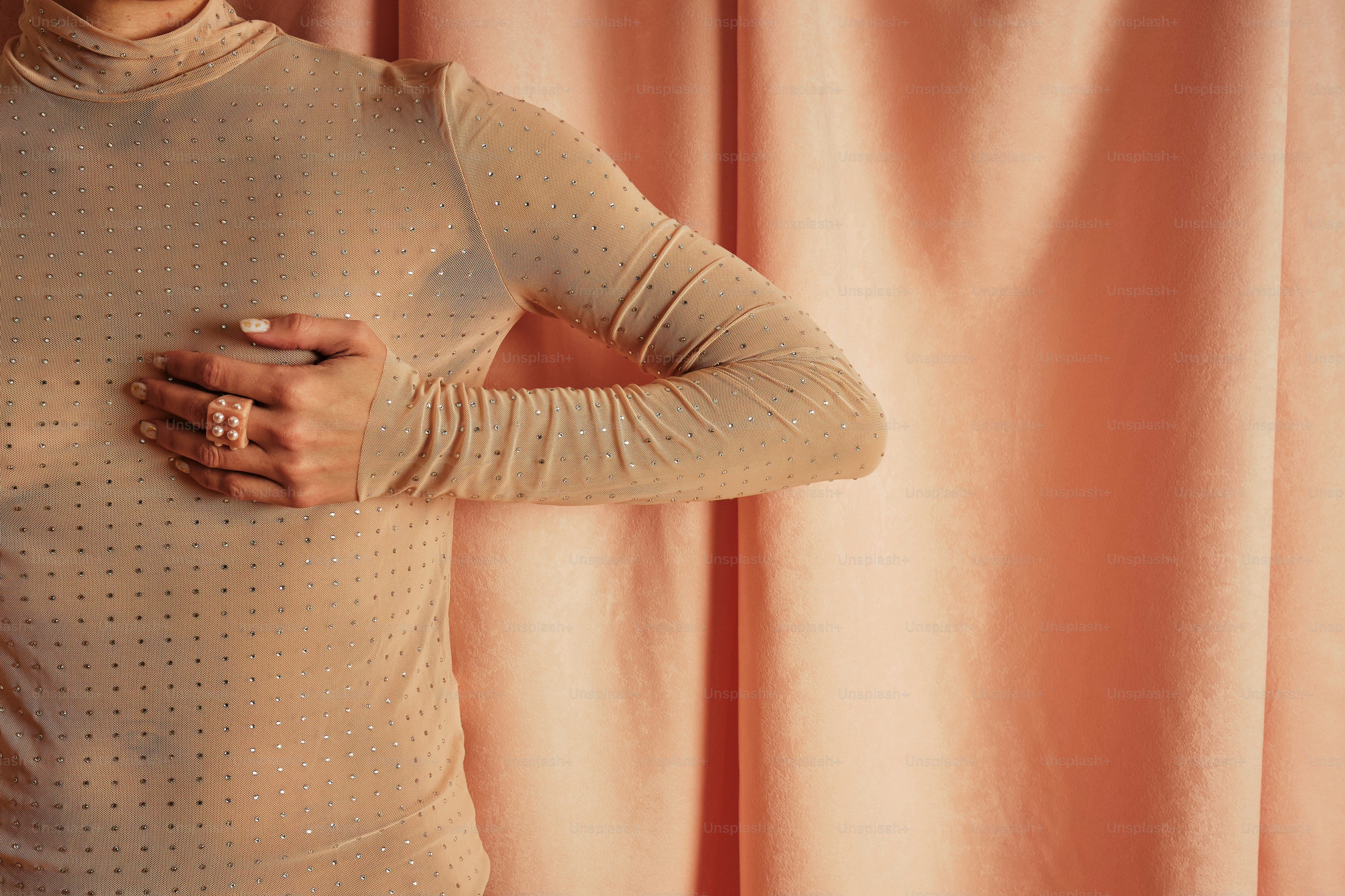 una donna in un vestito beige tiene la mano sul fianco