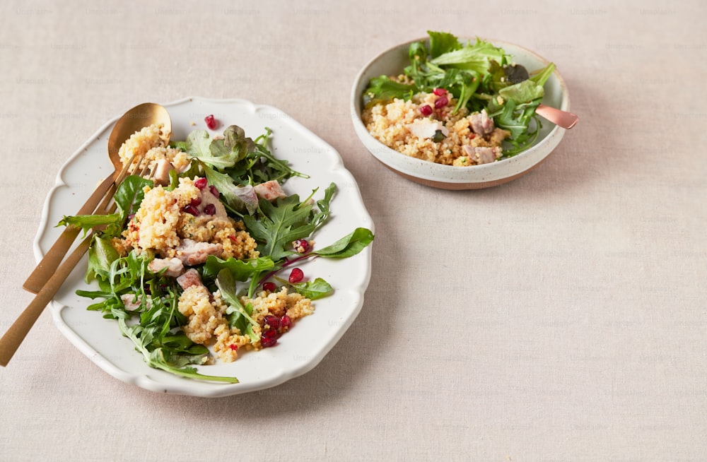 a white plate topped with a salad next to a bowl of salad