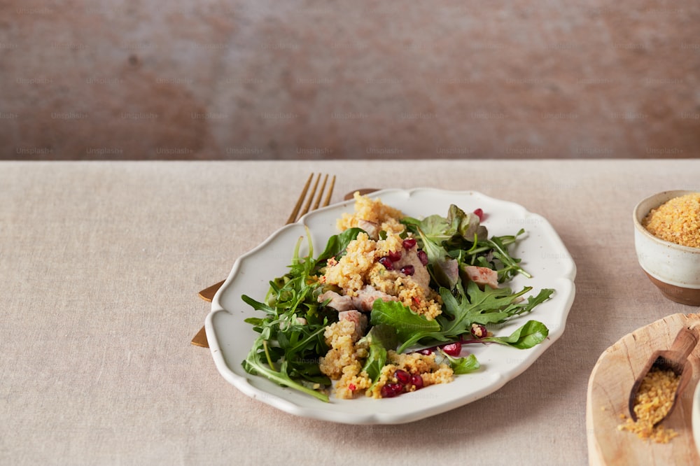 a white plate topped with a salad next to a wooden spoon