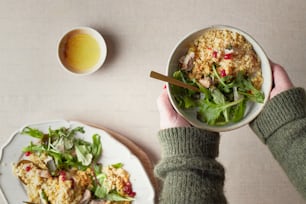 a person holding a bowl of food next to a plate of food