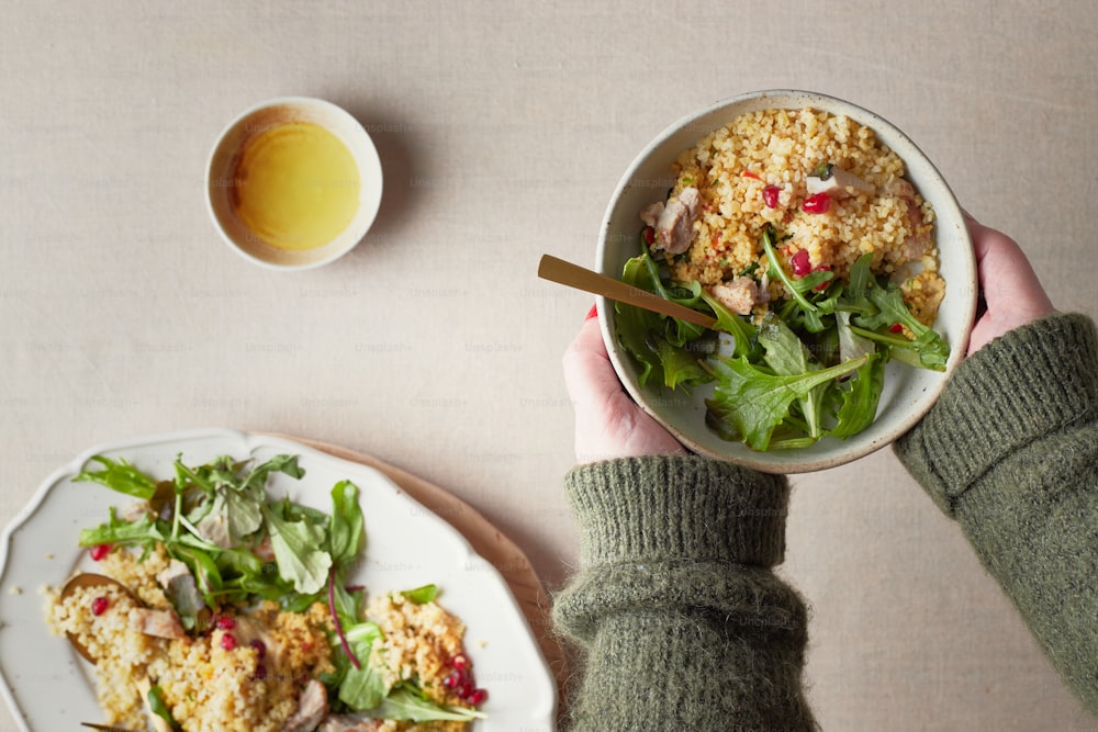 a person holding a bowl of food next to a plate of food