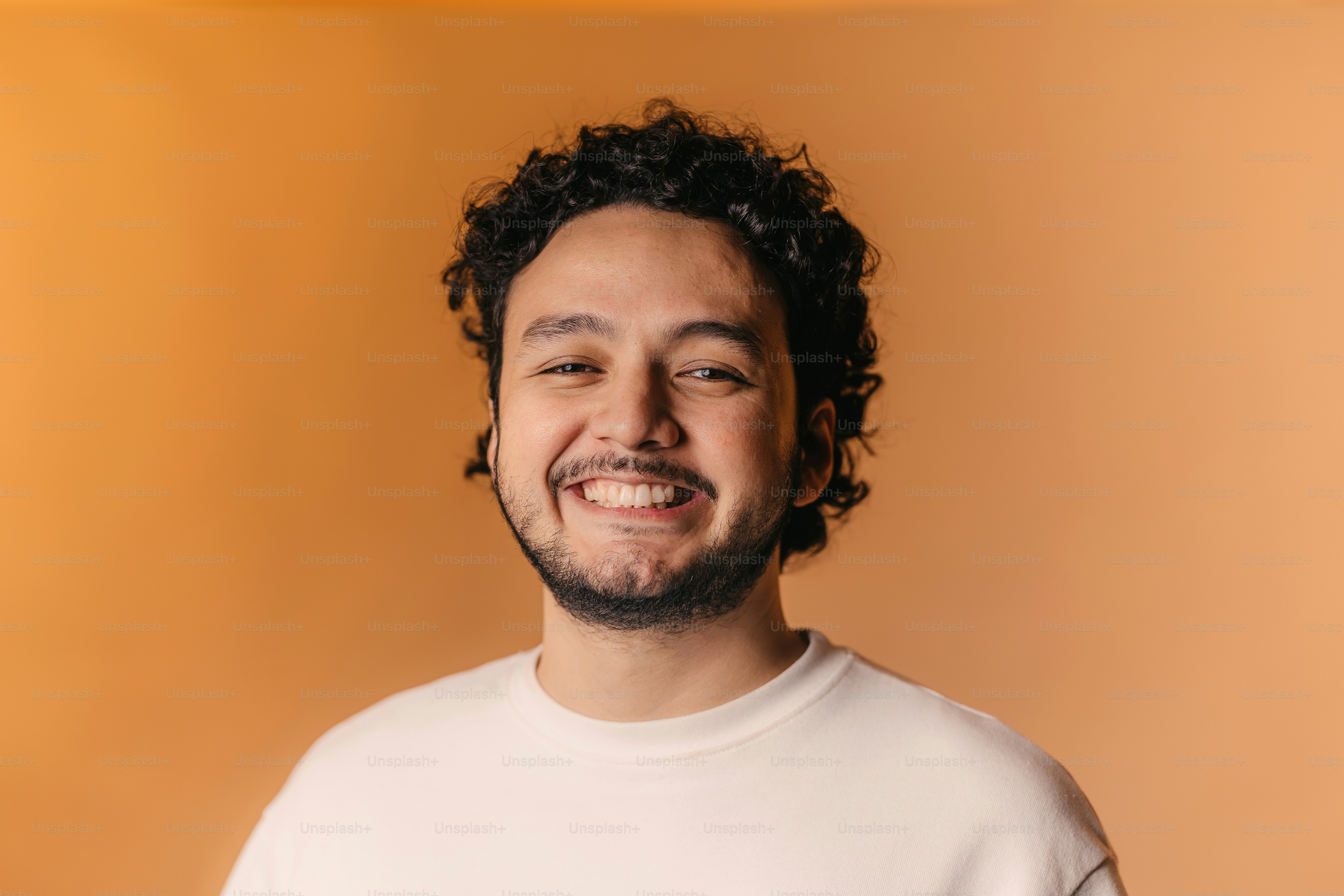 un uomo con i capelli ricci che sorride alla telecamera