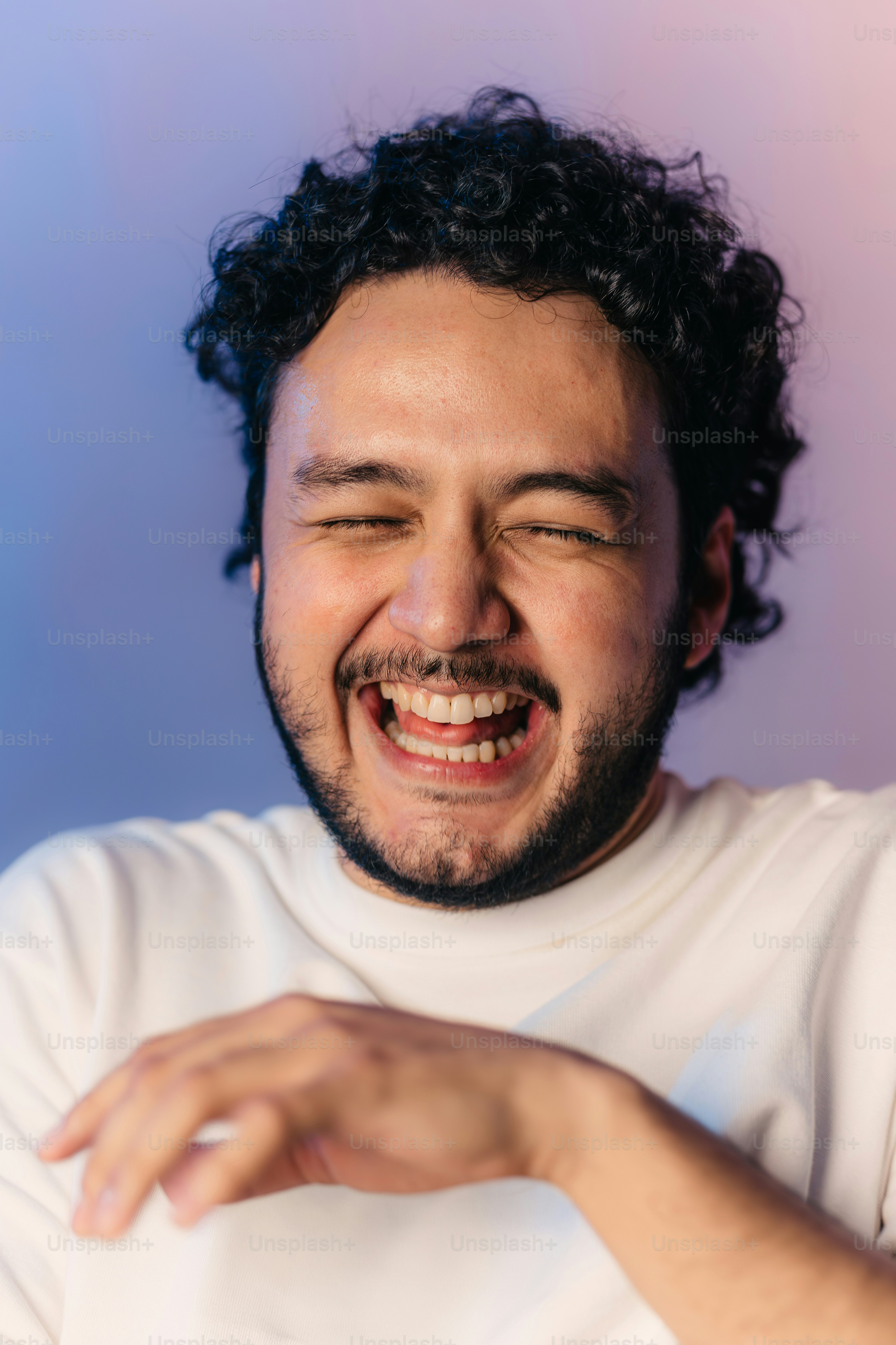 a man with curly hair laughing and holding a cell phone