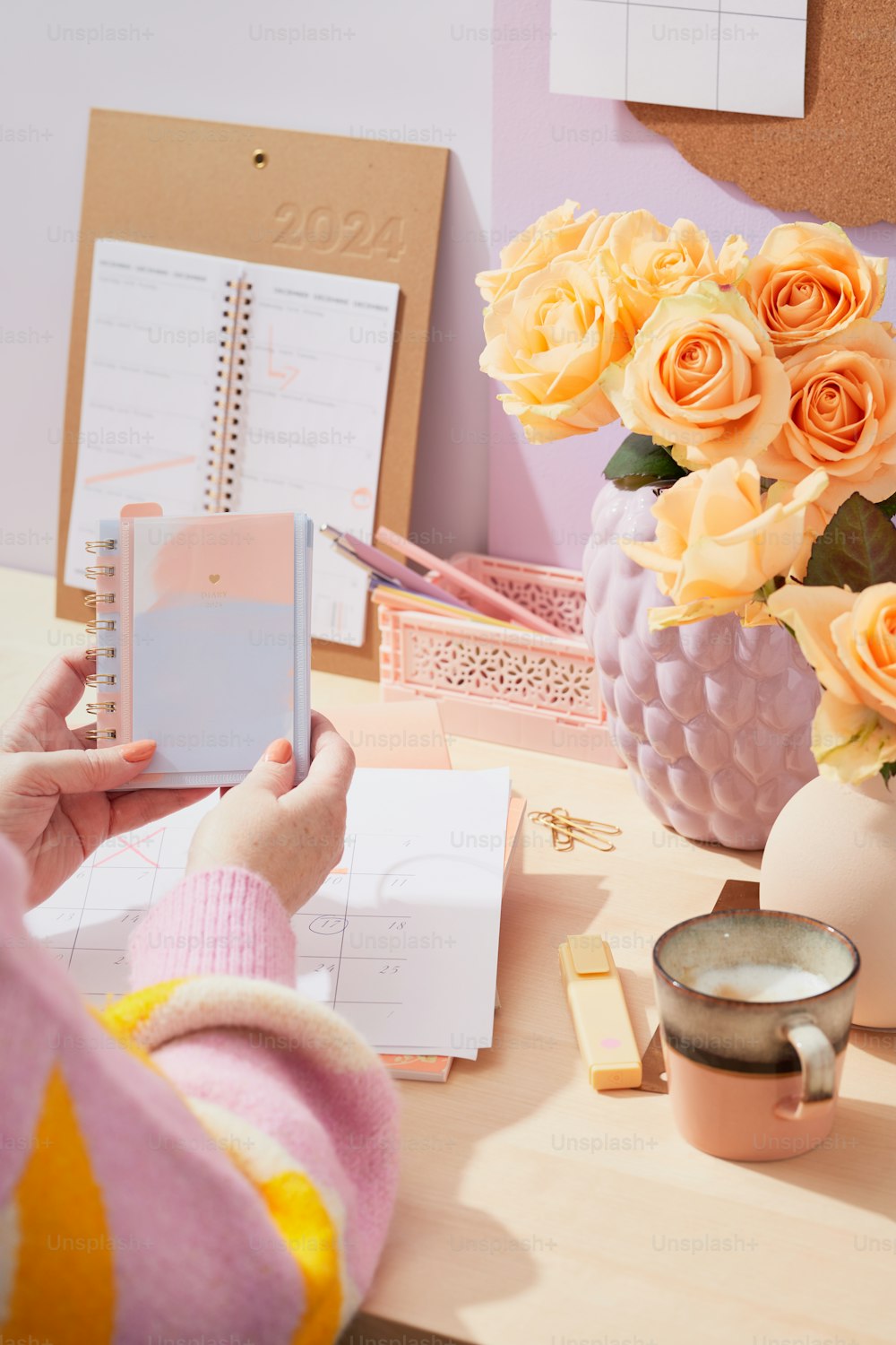 Eine Frau sitzt mit einem Notizbuch und Blumen an einem Schreibtisch
