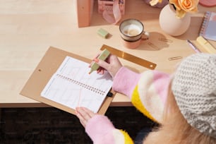 a woman sitting at a desk writing on a notepad