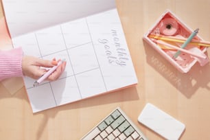 a person writing on a sheet of paper next to a keyboard