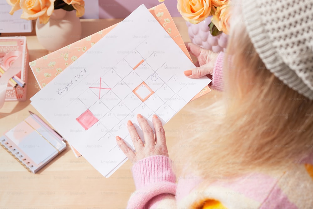 a woman is holding a calendar on a table