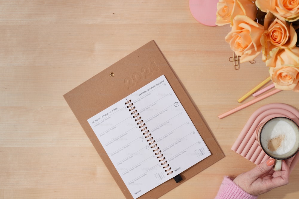 a person holding a cup of coffee next to a planner