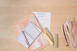 ein Holztisch mit einer rosa Tasche und einem Kalender