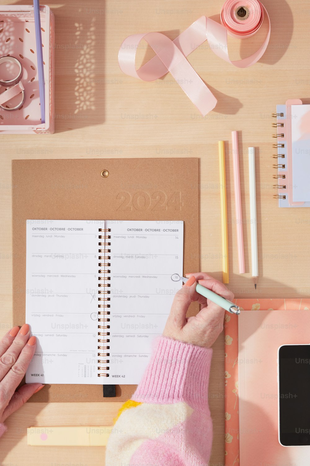 uma pessoa escrevendo em um caderno com uma fita rosa