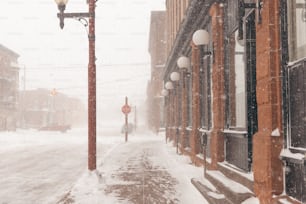 a street light on a snowy street with buildings in the background