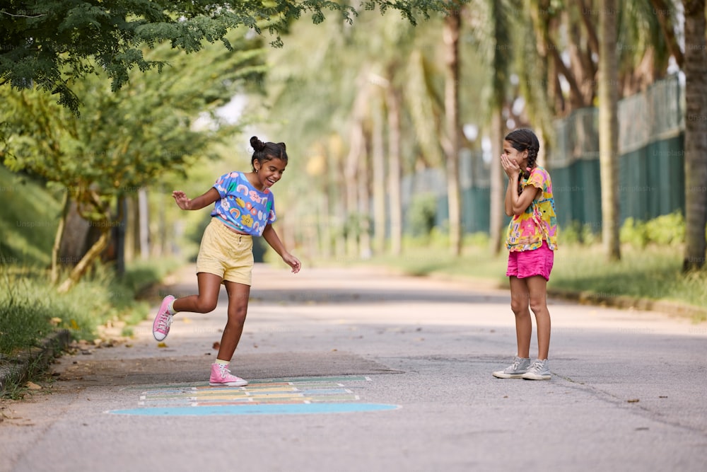 two young girls are playing on the street