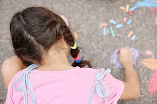 a little girl sitting on the ground drawing with crayons