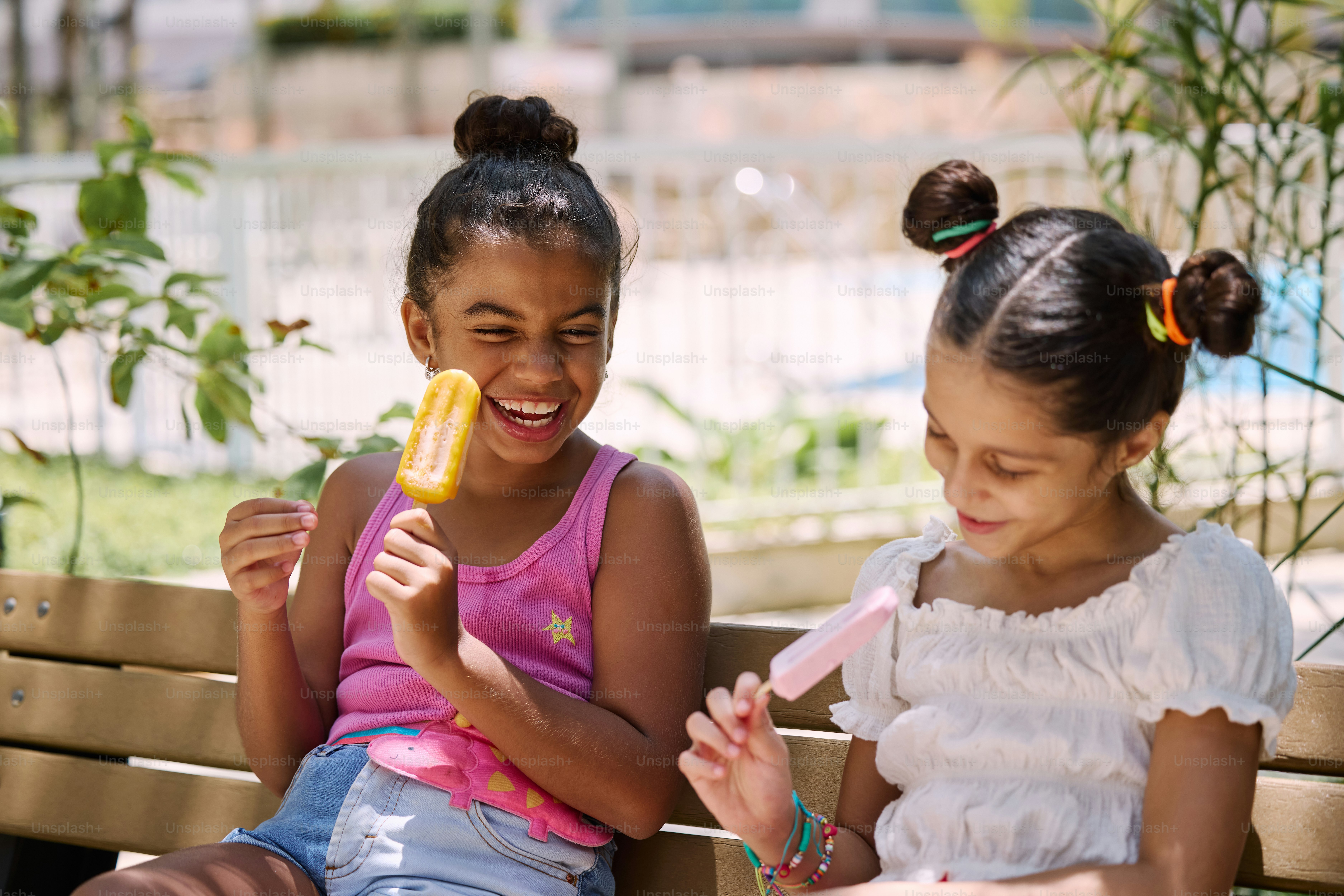 two young girls sitting on a bench with toothbrushes
