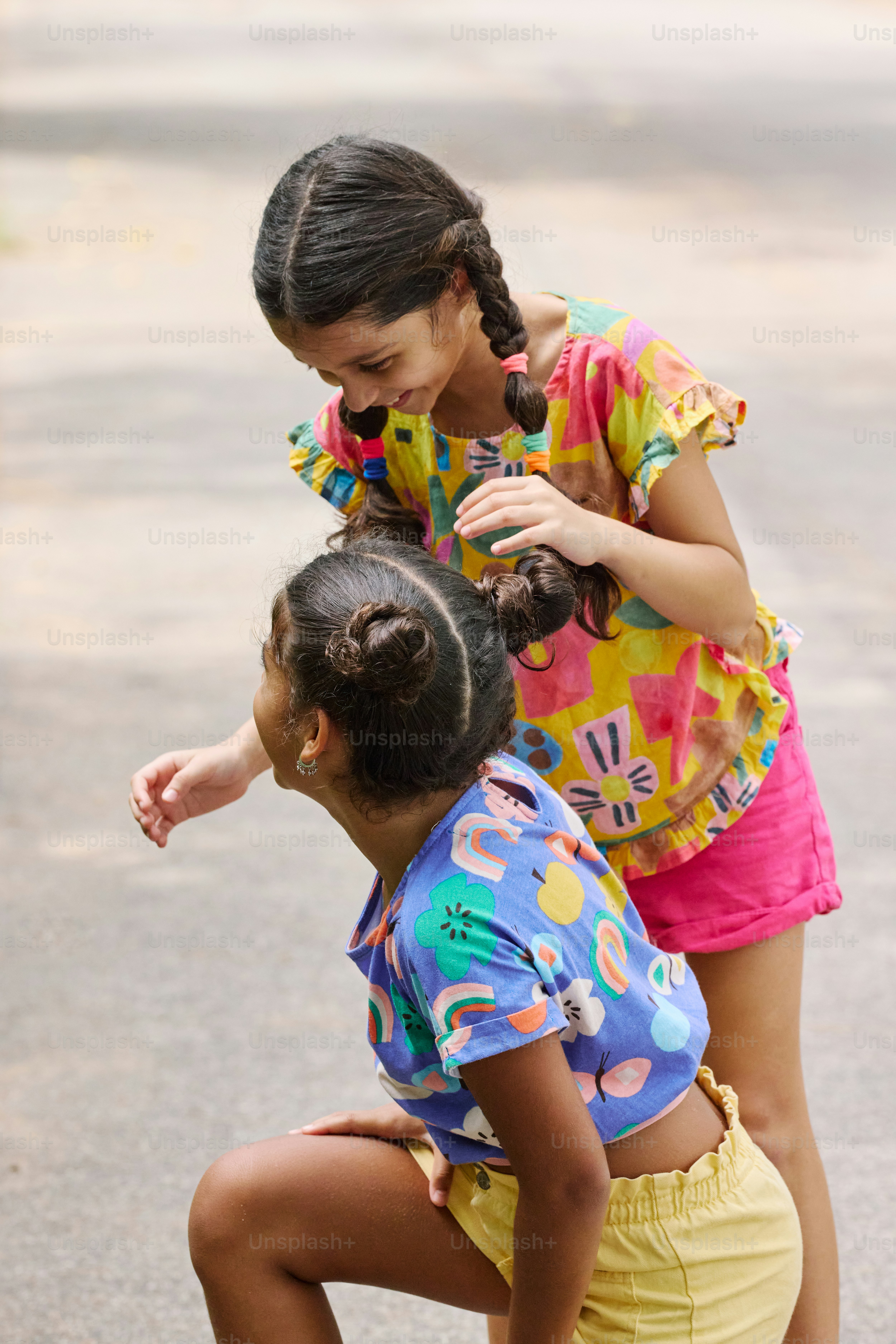 two young girls playing with a skateboard on the street
