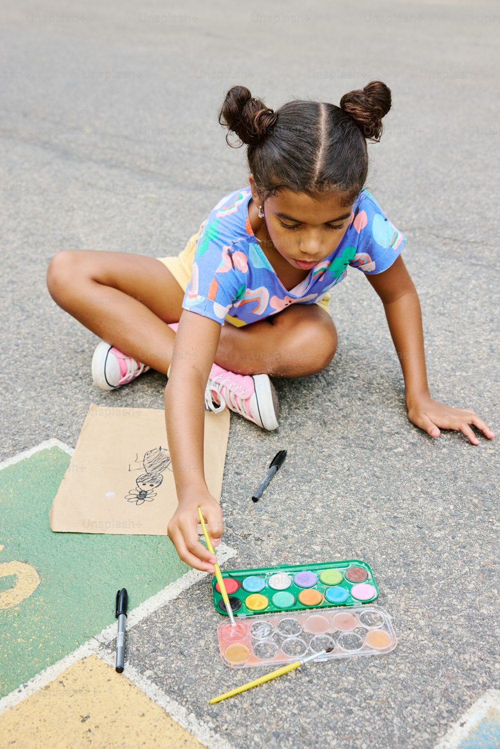 uma menina pintando um quadro no chão