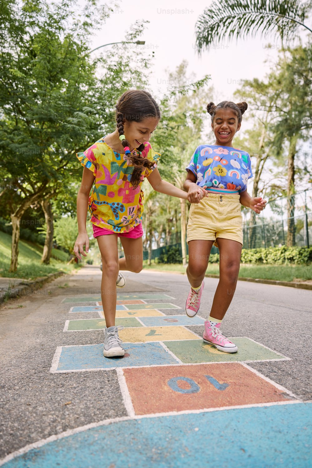 two young girls are running on a painted path