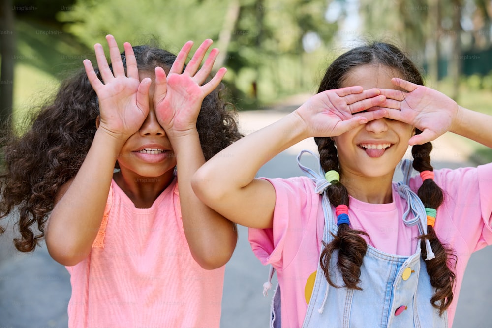 zwei kleine Mädchen, die ihre Augen mit ihren Händen bedecken