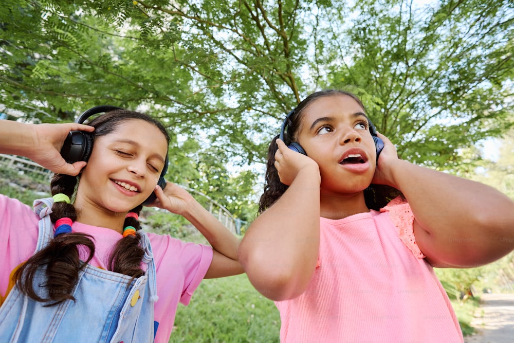 two young girls are listening to headphones