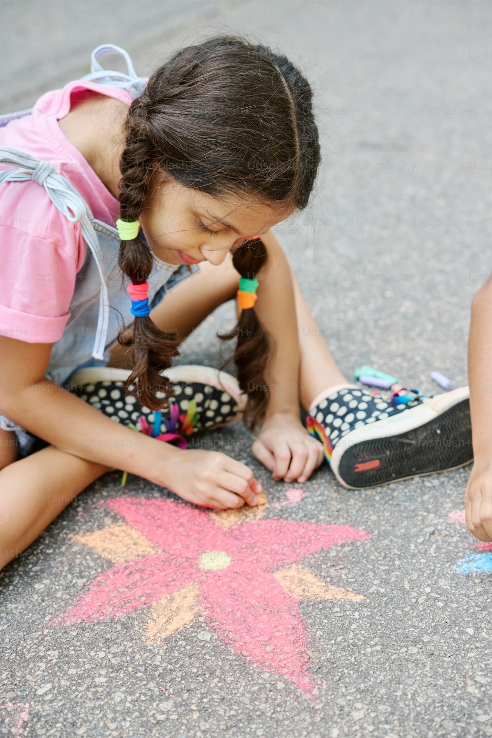 a little girl sitting on the ground drawing a star