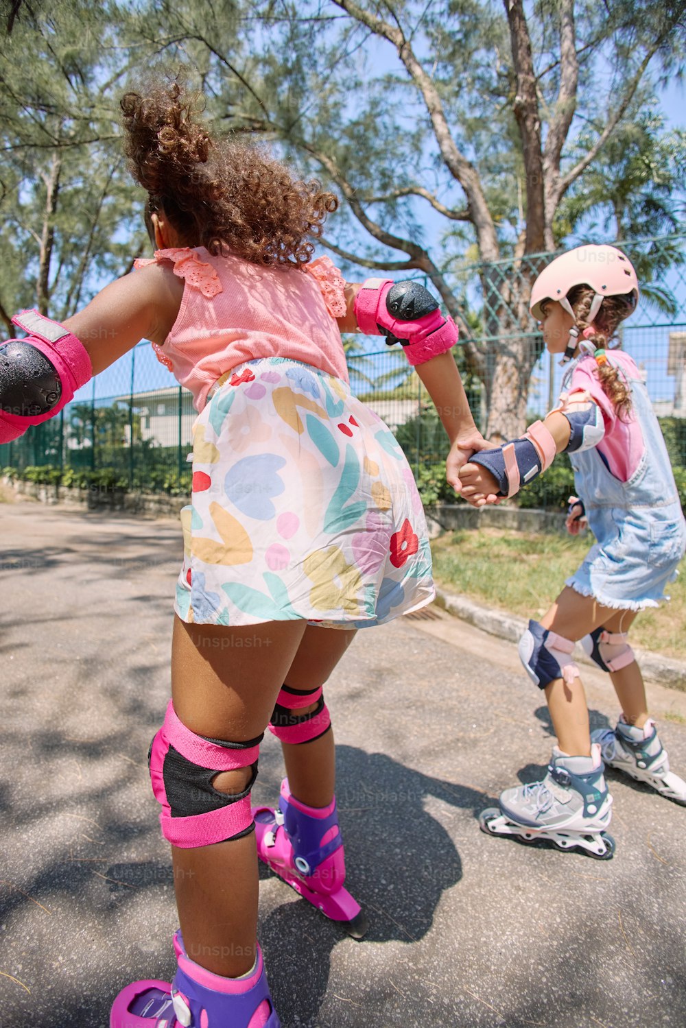 a little girl riding a skateboard next to another little girl