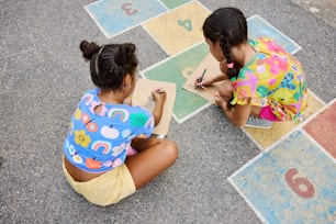 due giovani ragazze sedute a terra che scrivono numeri