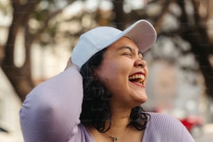 a woman laughing and wearing a hat on her head