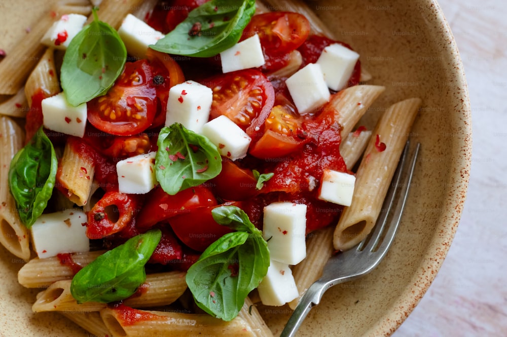 a bowl of pasta with tomatoes, mozzarella and basil