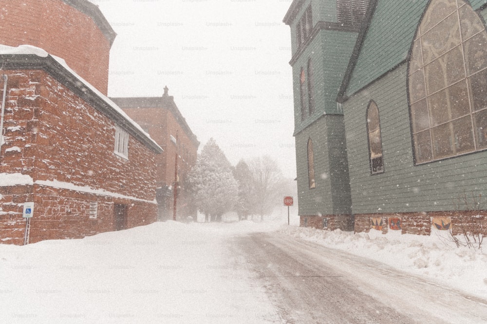 a snow covered street next to a brick building