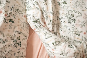 a bed with a floral comforter and pink sheets