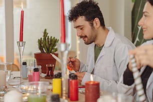 a man and woman sitting at a table with candles