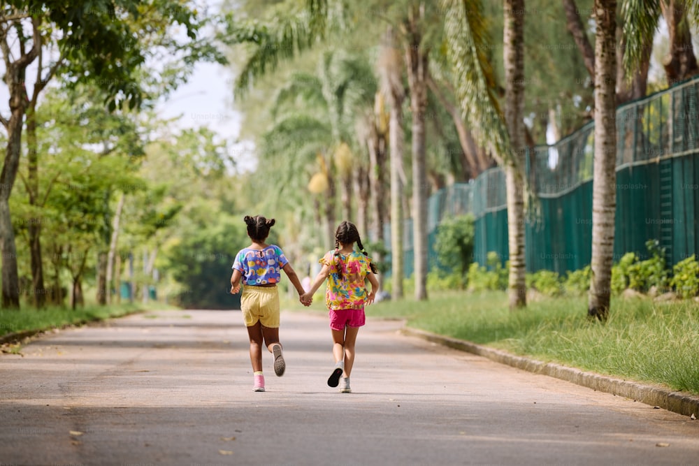 two girls running down a street holding hands